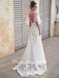 a woman in a white wedding dress standing on the street with her back to the camera