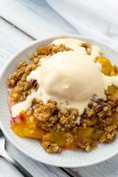 a white plate topped with fruit and ice cream on top of a wooden table next to utensils