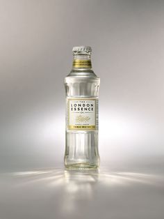 a bottle of london dry gin on a reflective surface with light coming from behind it