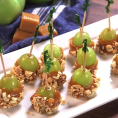 small appetizers with green apples and nuts on a white plate next to fruit