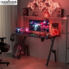 a computer desk with two monitors on top of it and some lights hanging from the ceiling