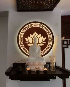 a buddha statue sitting on top of a wooden shelf in front of a circular wall decoration