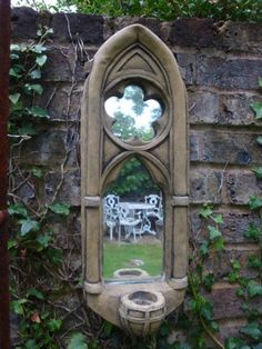 a mirror is hanging on the side of a brick wall with ivy growing around it