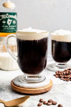 two mugs filled with hot chocolate and whipped cream on top of a wooden board