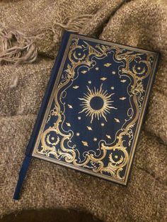 a blue and gold book laying on top of a blanket