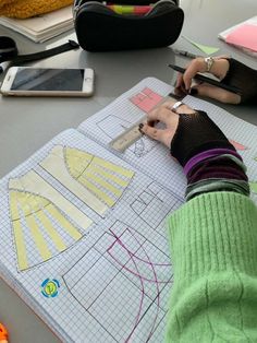 a person cutting out paper with scissors on a table next to other items and notebooks