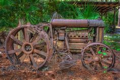 an old rusted out tractor sitting in the woods