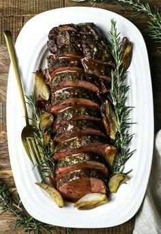 roast beef with rosemary garnish on a white platter