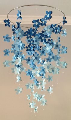 some blue and white paper flowers hanging from a circular chandelier in a room