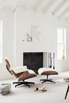 an eames chair and ottoman in front of a fireplace