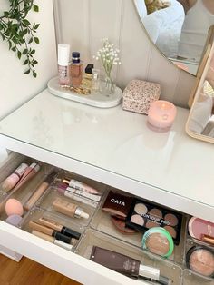 an open drawer with cosmetics and makeup products on the counter in front of a mirror