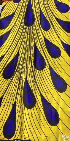 a yellow and blue peacock print fabric with black spots on it's tail feathers