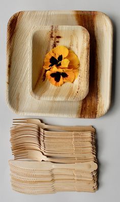 there is a wooden plate with flowers on it and several forks in front of it