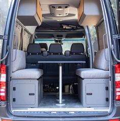 the back end of a van with two seats and a table set up in it