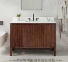 a white toilet sitting next to a bathroom sink under a mirror on top of a wooden cabinet