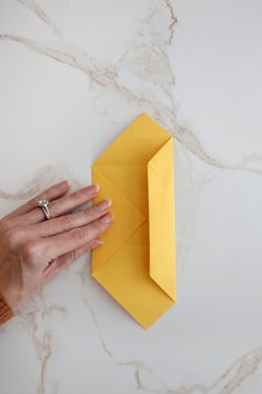 a person holding an origami piece on top of a marble counter with their hand