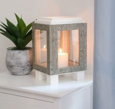 a candle holder sitting on top of a white table next to a potted plant