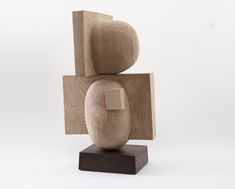 a wooden sculpture sitting on top of a wooden block in front of a white background