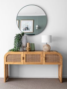 a wooden table topped with a mirror next to a lamp and vase on top of it