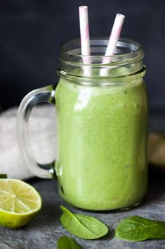 a green smoothie in a mason jar with two straws