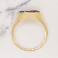 This beautiful and unique solitaire ring features a 2.19ct moval cut red garnet set in a sleek and elegant east west bezel setting! The garnet is a gorgeous rich red hue, and it has a beautiful play of light. The color is rich and luxurious, and it pairs perfectly with the yellow gold setting. The garnet’s elongated moval cut adds a unique touch. Combining aspects of the marquise cut and the oval cut, moval cuts are a rare find! The east west setting gives this classic ring a fashionable edge. A Formal Ruby Signet Ring With Bezel Setting, Modern Ruby Ring With Bezel Setting, Ruby Signet Ring With Bezel Setting For Formal Occasions, Formal Oval Cabochon Ruby Ring With Bezel Setting, Modern Yellow Gold Ruby Ring For Formal Events, Modern Yellow Gold Ruby Ring For Formal Occasions, Classic Ruby Ring With Tension Setting For Gift, Classic Ruby Ring With Tension Setting As Gift, Gold Ruby Ring With Tension Setting For Formal Occasions