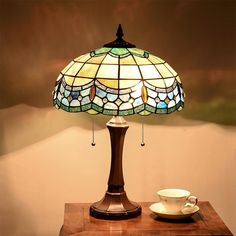 a lamp that is sitting on top of a table next to a cup and saucer