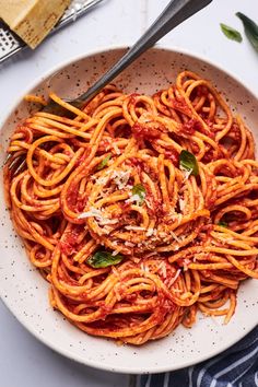 a white bowl filled with spaghetti and sauce