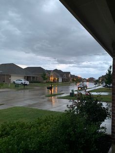 rain is falling on the street in front of houses