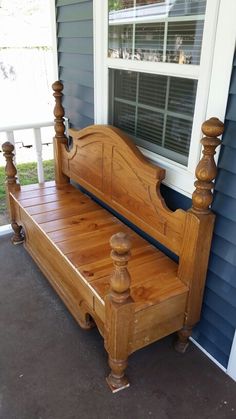 a wooden bed sitting on top of a porch next to a blue house with white windows