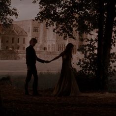 a man and woman holding hands in front of a castle