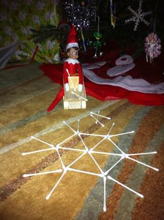 an elf is sitting on the floor next to christmas decorations