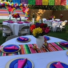 the table is set with colorful plates and napkins for an outdoor party or celebration