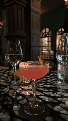 two wine glasses sitting on top of a table next to each other with drinks in them