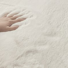 a person's hand on top of a fluffy white bed sheet that has been made