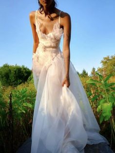 a woman in a white dress standing on a rock