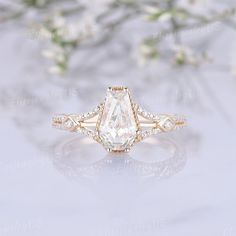 an engagement ring with a pear shaped diamond surrounded by small white flowers and greenery