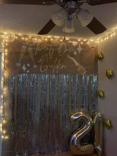 a large number two balloon sitting on top of a table next to a window covered in tinsel