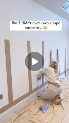 a woman is painting the wall with tape