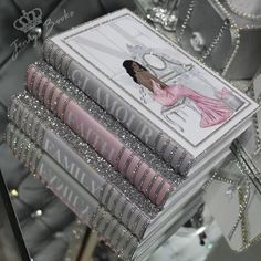 a stack of books sitting on top of a table next to a mirror covered wall