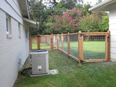 an air conditioner sitting in the grass next to a fenced off backyard area