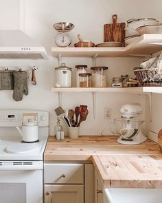 a white stove top oven sitting inside of a kitchen next to a wooden counter topped with pots and pans