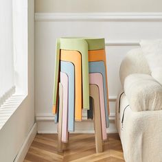 four colorful stools sitting on top of a wooden floor next to a white couch