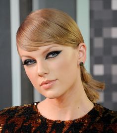 a close up of a woman with blue eyeshadow and hair in a ponytail