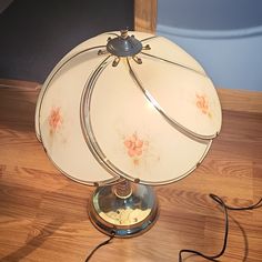 a table lamp sitting on top of a wooden floor next to a light switch and plugged in