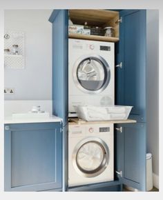 a washer and dryer in a room with blue cupboards on the wall