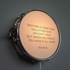 a drum with a quote written on it hanging from the side of a gray wall