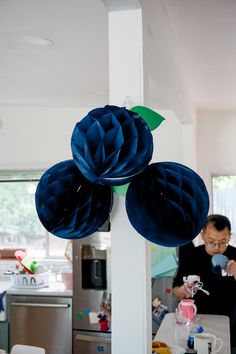 two large blue flowers are hanging from a pole in the kitchen, while a man looks on