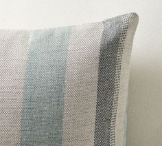 a blue and white striped pillow sitting on top of a couch next to a wall