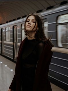 a woman standing in front of a train at a subway station with her eyes closed