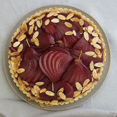 a pie with almonds and beets on top is sitting on a white table cloth